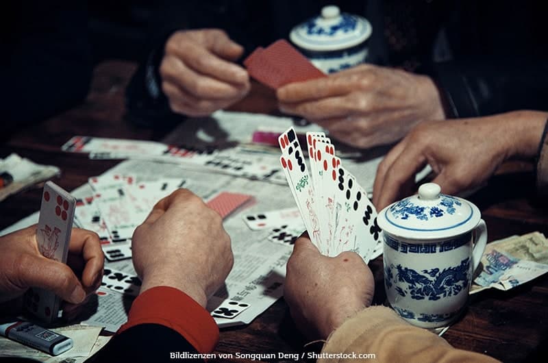 Asiatische Männer spielen Kartenspiel mit Spielkarten