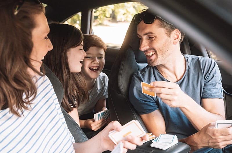 Eine junge Familie spielt Reisespiele im Auto