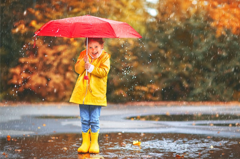 Junges Mädchen steht im Regenwetter lustig