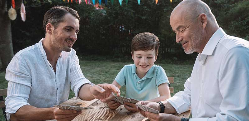 Opa, Vater und Enkel-Sohn spielen gemeinsam Skat. Zusammen spielen macht Spaß.