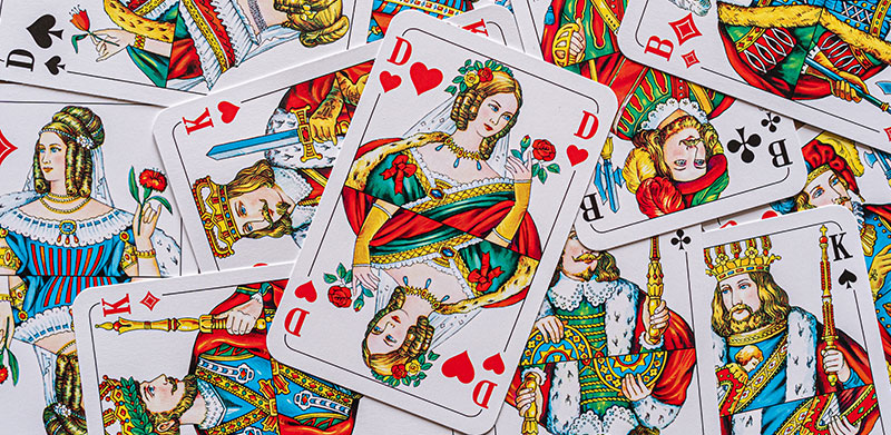 Verschiedene Spielkarten liegen auf Stapel. Herz Dame liegt obenauf. Bube Dame König – ASS Altenburger.