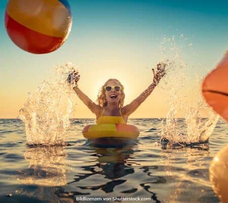Kind schwimmt im Sommer mit Schwimmreifen im Wasser, trägt Sonnenbrille, lacht und wirft Wasserball. Im Vordergrund schwimmt eine aufblasbare Gummiente. Sommeranfang, ASS Altenburger