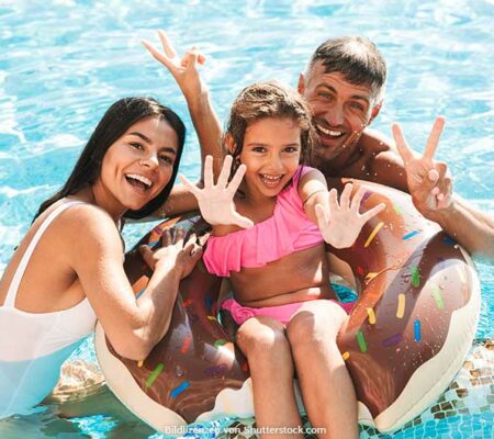 Familie steht im Wasser im Pool lacht und grüßt. Aktivitäten mit Kindern, ASS Altenburger