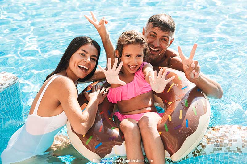 Familie steht im Wasser im Pool lacht und grüßt. Aktivitäten mit Kindern, ASS Altenburger