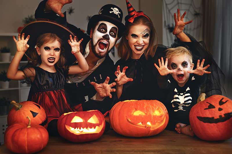 Familie mit Mutter Vater Sohn und Tochter sitzt in Halloween Kostümen am Tisch und macht Grimassen. Einfache Halloweenkostüme, ASS Altenburger