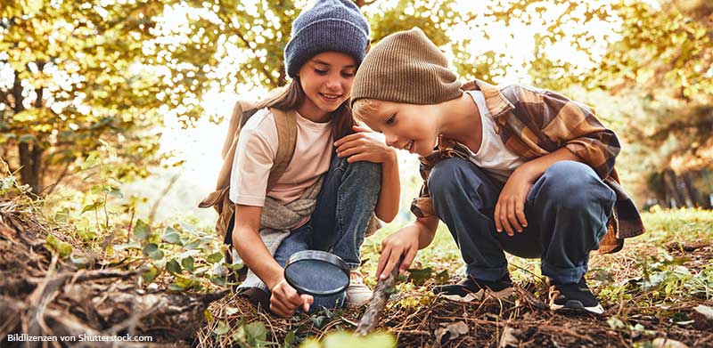Junge-und-Maedchen-untersuchen-Waldboden-mit-Lupe-Soziale-Kompetenz-bei-Kindern-ASS-Altenburger