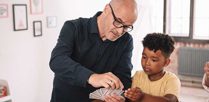 Opa spielt mit Enkel im Kinderzimmer Karten. Kartenspiel zu zweit, ASS Altenburger