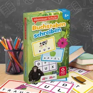 Das Abenteuer Schule Buchstaben schreiben Spiel steht auf einem Schultisch. Unter dem Tisch liegen einige der dazugehörigen Spielkarten. Neben dem Spiel stehen Stifte und ein Bücherstapel. Im Hintergrund ist unscharf eine Tafel zu erkennen.