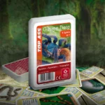 Das Top ASS Giftige Tiere Trumpfspiel steht in einem Urwald auf einem hölzernen Untergrund. Unter dem Spiel liegen einige der dazugehörigen Spielkarten.