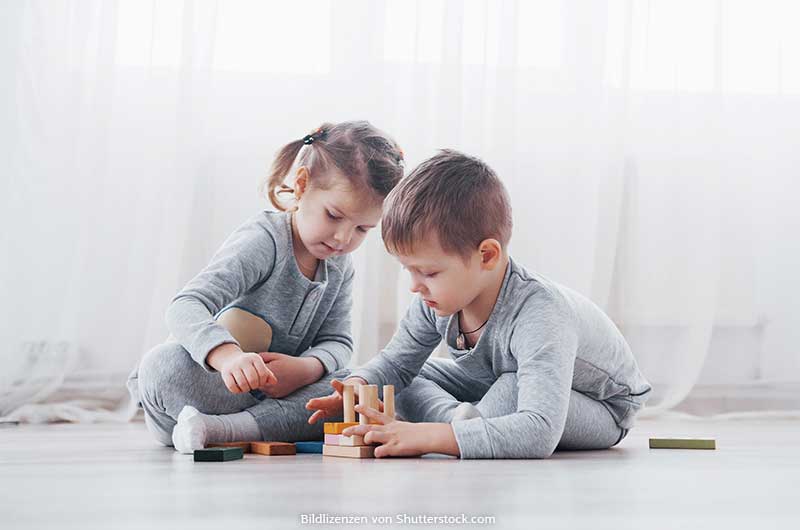 Ein Junge und ein Mädchen spielen mit Bauklötzen auf dem Boden. Lernspiele, ASS Altenburger