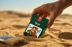 Kartenspiel wird von Hand aus Wüstensand gehoben. Geschichte der Spielkarten, ASS Altenburger