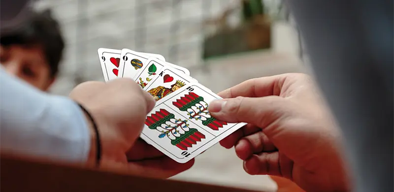 Nahaufnahme einer Hand, die einen Fächer Skatkarten hält. Kartenkultur, ASS Altenburger