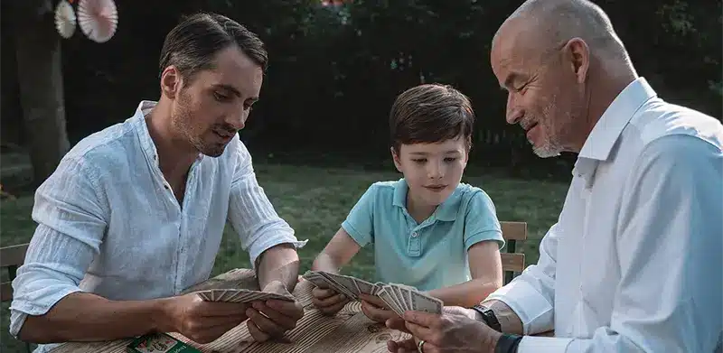 Enkel, Vater und Opa spielen Doppelkopf an Holztisch im Garten. Doppelkopf, ASS Altenburger