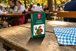 Kartenspiel Schafkopf steht auf Holztisch in Biergarten. An den anderen Tischen sitzen verschiedene Menschen. Schafkopf, ASS Altenburger