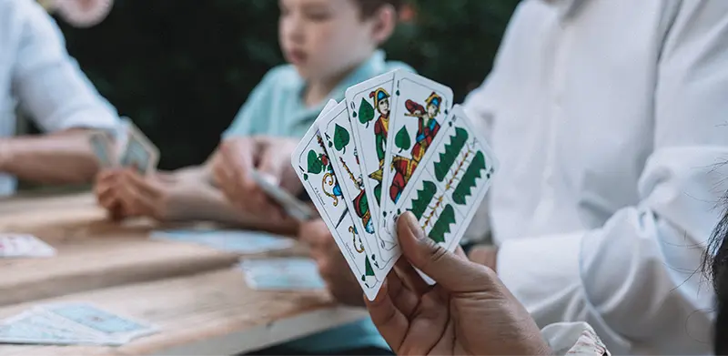 Nahaufnahme von fünf Spielkarten in einem Fächer in einer Hand. Schafkopf, ASS Altenburger