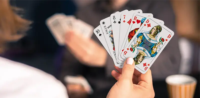 Eine Frau hält Spielkarten mit französischem Blatt in der Hand. Kartenfarben, ASS Altenburger