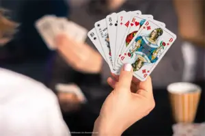 Eine Frau hält Spielkarten mit französischem Blatt in der Hand. Bube, Dame, König, ASS Altenburger